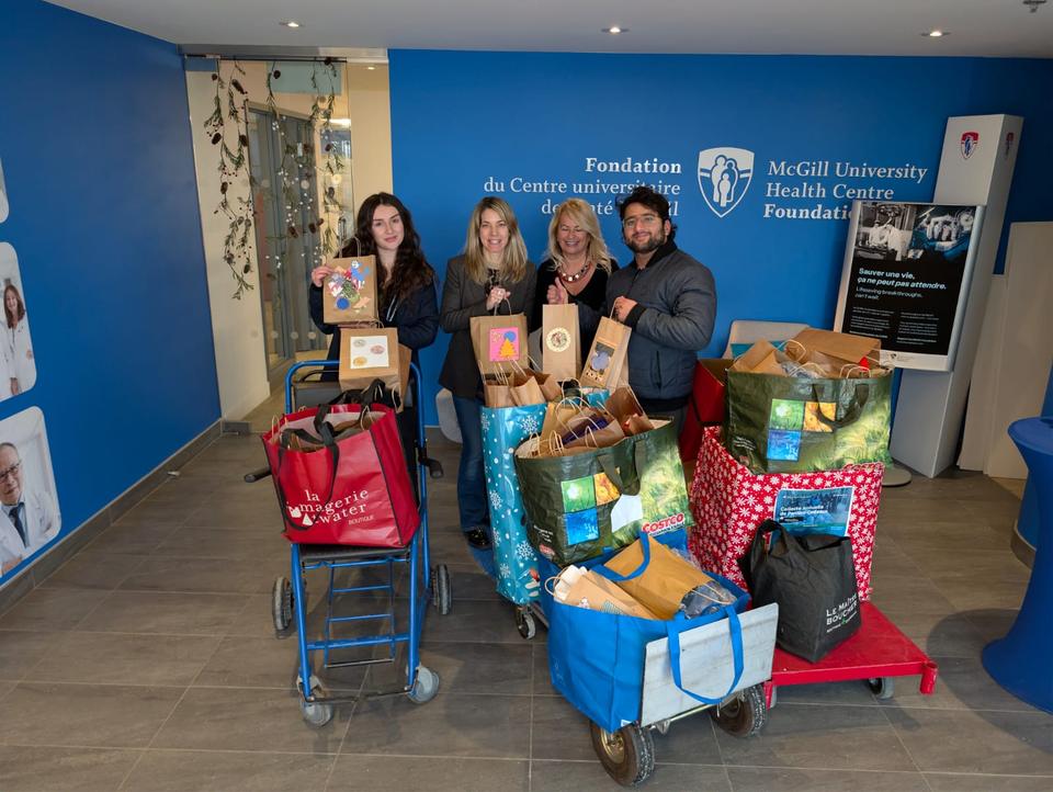 Five volunteers stand with carts piled high with gift bags in a lobby.
